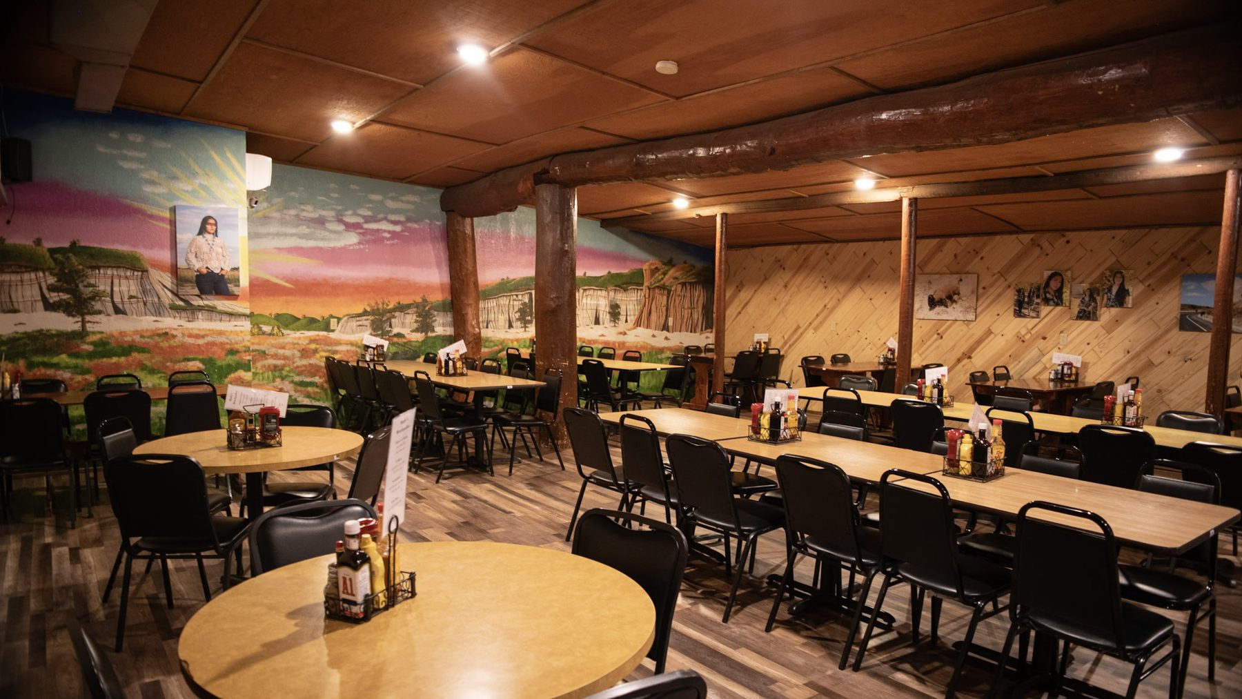 The back dining room at Burly's Roughrider, tables set beneath Rhoda Dutchak's hand-painted Badlands mural